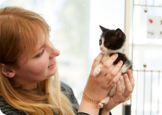 A woman holding a kitten in her hands