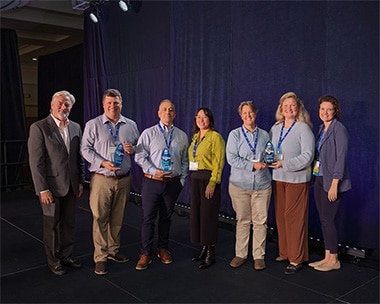 Seven professionals holding Wagsies awards on stage.