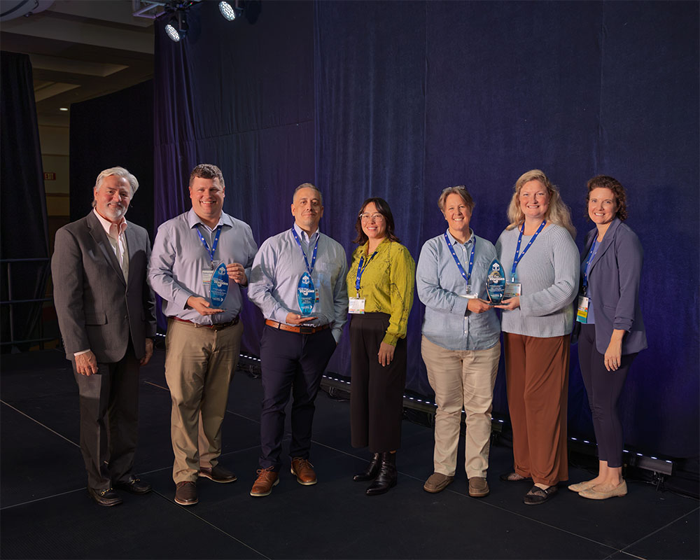Seven professionals holding Wagsies awards on stage.