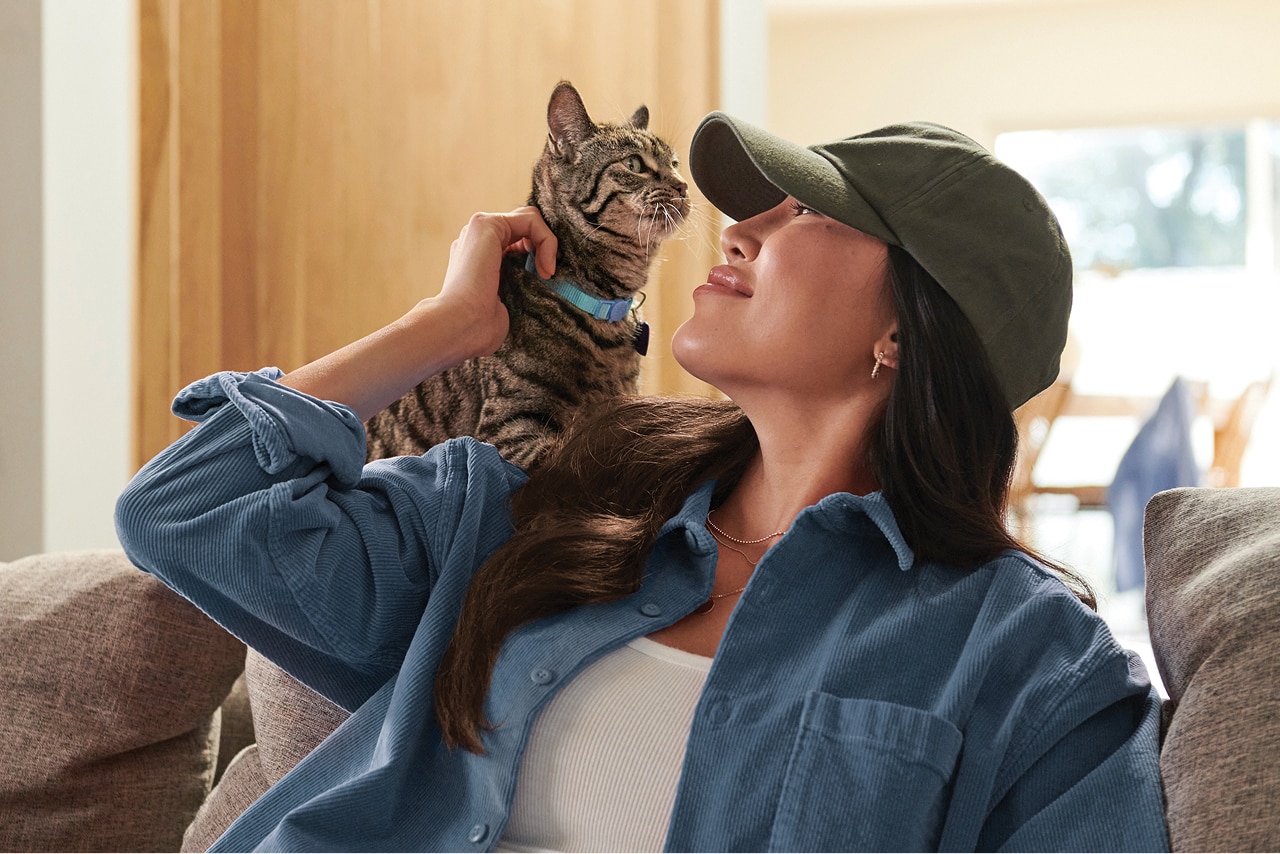 A brown-white cat sitting in a woman's lap looking outside a window
