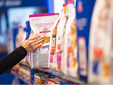 Hand taking a bag of Hill's pet food from a store shelf