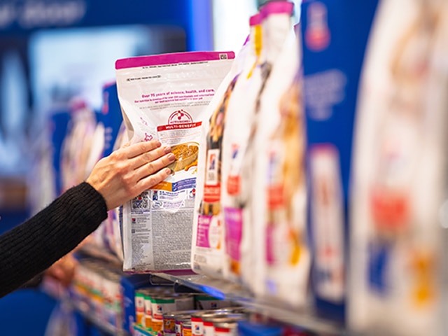 Hand taking a bag of Hill's pet food from a store shelf